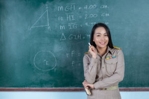 thai teacher in official outfit  teaching in front of  backboard